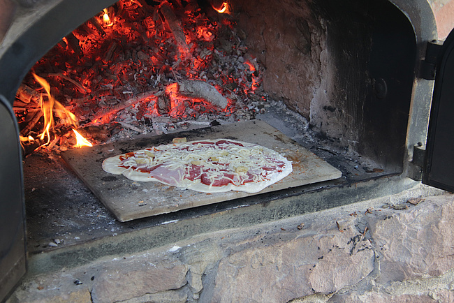 Leckere Pizza im Steinofen mit Feuer