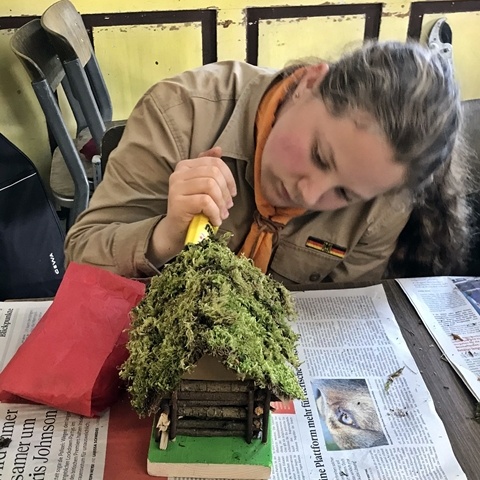 Pfadfinderin klebt Moos auf Hütte