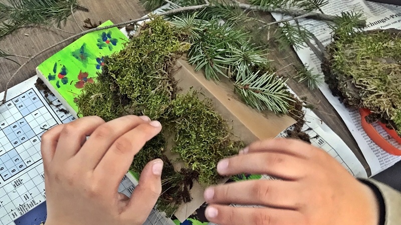 Ein Kind verschönert die selbstgebaute Holzhütte