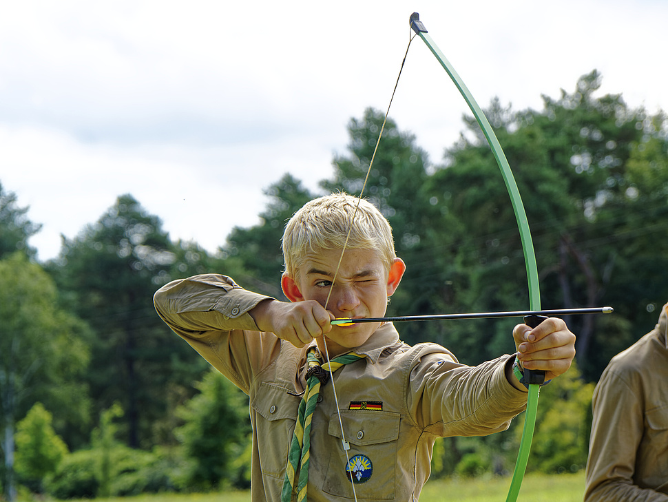 Pfadfinder spannt Bogen Pfadfinder beim Bogen Schießen