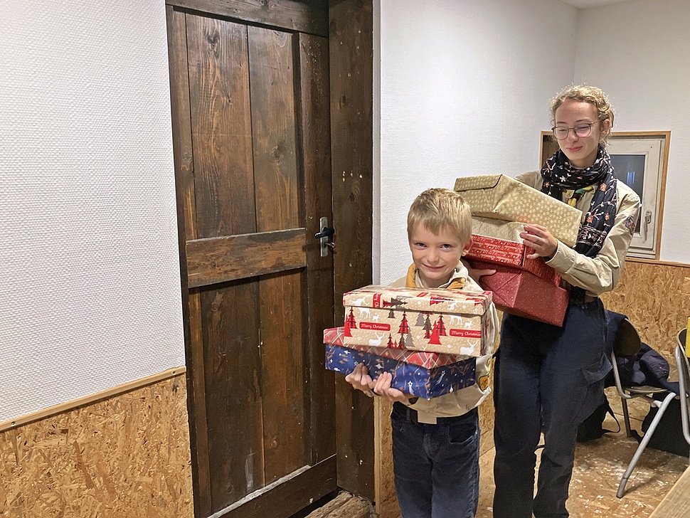 Zwei Pfadfinder mit einem Stapel Geschenke in der Hand