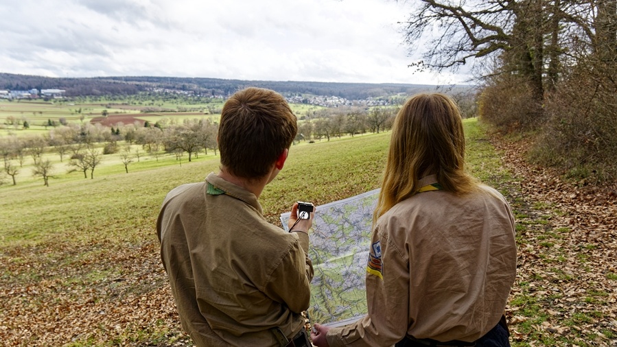 Pfadfinder schauen auf Karte Pfadfinder halten eine Karte und einen Kompass in der Hand